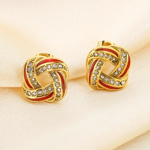 Macro shot of gold-plated twisted earrings with red enamel and pavé rhinestones
