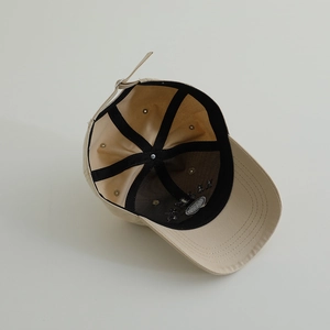 Inside view of a beige cotton baseball cap with adjustable metal buckle and stitched seams
