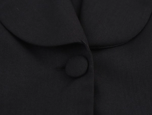 Detail of round neckline with fabric-covered button on black twill textured vest