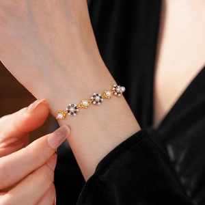 Close-up of vintage flower bracelet with pearls and blue gems on model's wrist