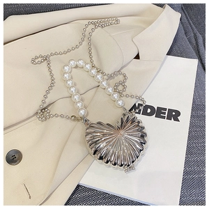 Detail of silver heart-shaped shell textured evening bag with pearl handle and chain