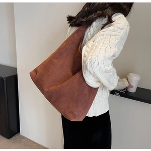 Detail of a brown suede tote bag showing soft matte texture and large capacity design