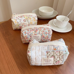 Floral quilted cotton makeup pouch with zipper closure on a cozy wooden tabletop