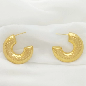 Detail of gold U-shaped earrings with hammered texture on white fabric background