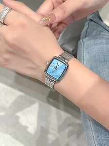 Close-up of a square blue dial watch with silver mesh band on a female wrist