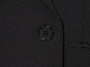 Close-up of a black four-hole button on high-quality woven blazer fabric texture