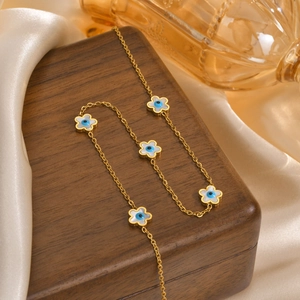 Detailed view of evil eye flower pendants on a gold chain over a wooden box