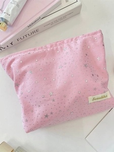 Pink fabric cosmetic bag with silver star sequins and brand label for travel storage