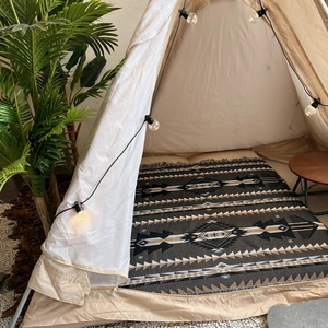 Close-up of bohemian tribal pattern picnic blanket inside a cozy camping tent setup