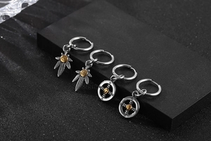 Close-up of retro stainless steel hoop earrings with maple leaf and cross pendants
