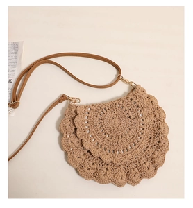 Detailed view of the crochet weave texture and adjustable brown leather strap on bag