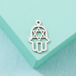 Macro view of silver Hamsa hand pendant with cutout Star of David on mint green stand