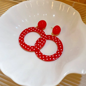Retro red resin hoop earrings with white polka dots on a white shell-shaped dish