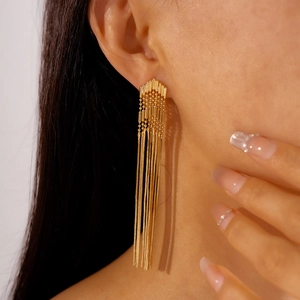 Close-up of elegant gold long tassel arrow earrings worn by a model in a high-end shot