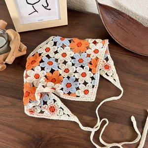 Close-up of handmade crochet flower bandana with hollow floral pattern on wood surface