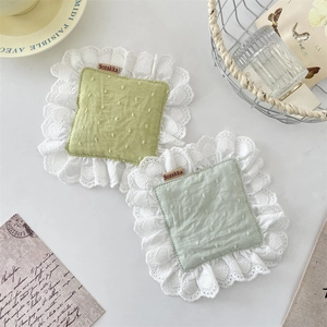 Detail of square cotton coasters featuring white lace trim and delicate polka dot embroidery