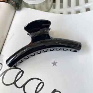 Close-up of a large glossy black hair claw clip for French twist styling on white paper
