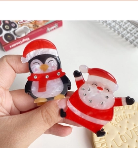 Gros plan de pinces à cheveux Père Noël et pingouin en acrylique avec strass brillants