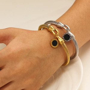 Braided gold and silver rope bracelets featuring Roman numeral pendants on wrist