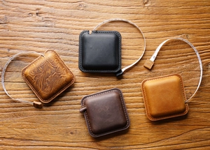 Flat lay view of square vintage leather tape measures in various colors on a wood table