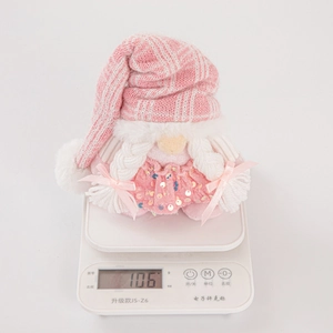Pink sequin knit Christmas gnome plush on a scale showing a 106g weight measurement