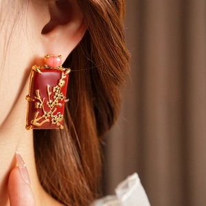 Gros plan d'une boucle d'oreille émaillée vintage avec relief doré et gemme rose