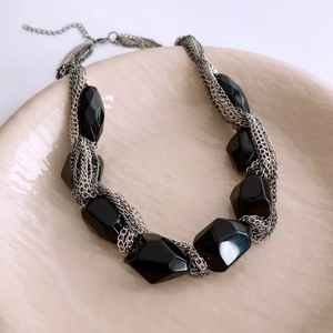Close-up of chunky silver layered chain necklace with large faceted black stones in a tray