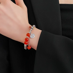 Close-up of red agate dragon bracelet with Fortune tag and lucky cat charm detail