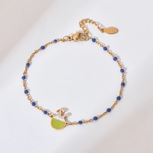 Detail view of a gold stainless steel bracelet with blue beads and a coconut drink charm