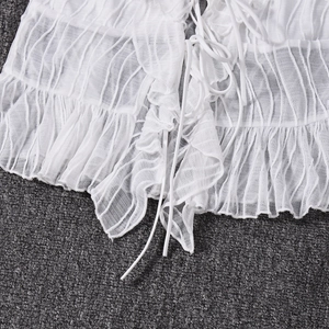 Detail of white striped crop top featuring ruffle trim edges and drawstring ties