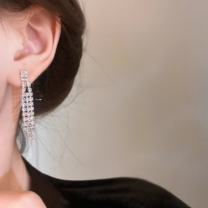 Close-up of sparkling silver tassel earrings with crystal rhinestones on model