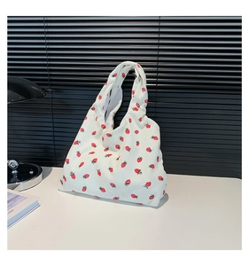 Close-up of a white corduroy tote bag featuring red strawberry embroidery texture