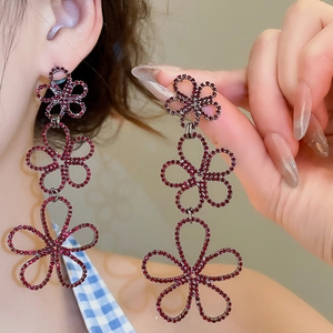 Detailed close-up of long red floral drop earrings with sparkling rhinestones for party wear