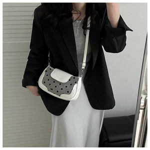 Vue détaillée du sac bandoulière en cuir blanc et toile à pois porté avec une tenue décontractée