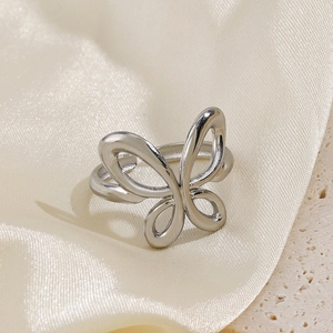 Polished silver butterfly open ring made of stainless steel on beige silk and stone