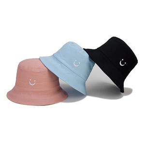 Detail of embroidered smiley face on cotton canvas bucket hats in pink, blue and black