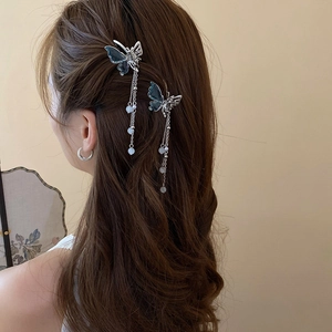 Détail de la pince à cheveux papillon argentée avec perles et ailes bleues sur cheveux