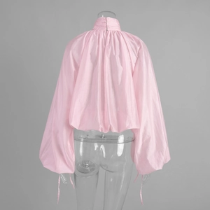 Detail of light pink high-neck blouse with lantern sleeves and pleated fabric texture