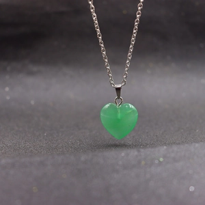 Macro shot of a green heart-shaped crystal stone pendant with a silver necklace chain