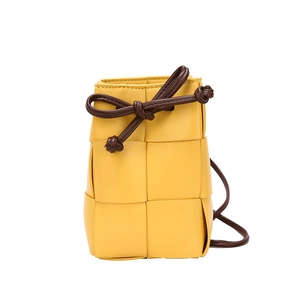 Woven leather mini bucket bag in yellow with dark brown knot shoulder strap on white backdrop