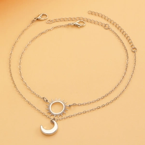 Close-up of silver sun and moon pendant necklaces with lobster clasp and extension chain