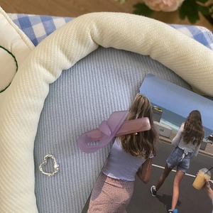 Detail view of purple acetate hair claw and silver heart ring on blue textured fabric