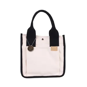 Borsa tote in tela bicolore con manici neri e tasca frontale per uso quotidiano