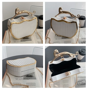 Detail view of a white striped box bag with golden cat-shaped handle and chain strap