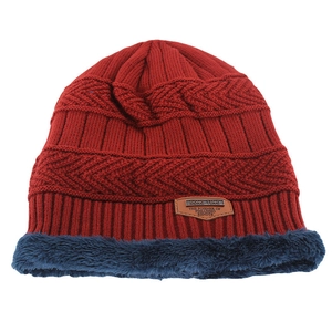 Detail view of burgundy knit beanie with blue faux fur lining and leather patch