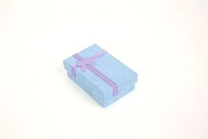 Detail of light blue jewelry gift box with purple satin ribbon and bow on white background