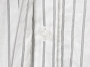 Close-up of a white striped shirt with cotton texture and a translucent button detail