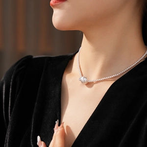 Dettaglio collana di perle e zirconi su modella con abito di velluto nero e luce soffusa