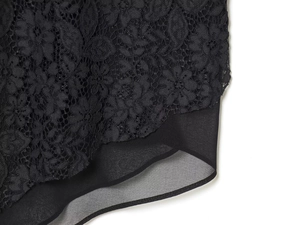 Close-up of black floral lace texture with semi-transparent chiffon hem stitching