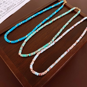 Macro shot of colorful Shoushan stone necklaces with gold metal spacers on wood tray